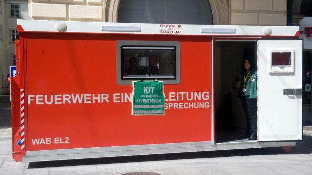 Ein roter Feuerwehr-Einsatzleitungs-Container der Stadt Graz mit einer Frau im Inneren.