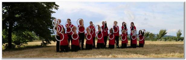 Eine Gruppe von Mädchen in roten T-Shirts posiert mit weißen Ringen auf einem Feld.