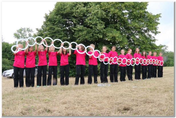 Eine Gruppe junger Frauen hält eine Kette aus weißen Ringen in die Höhe.