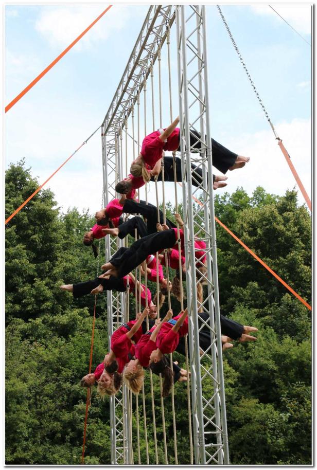Eine Gruppe von Frauen hängt an Seilen, die an einem Metallgerüst befestigt sind.