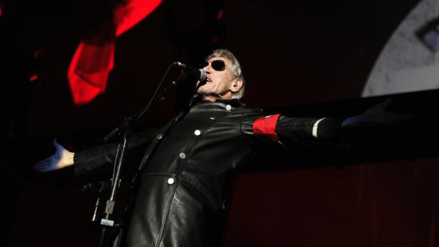 Roger Waters tritt während eines Konzerts in einer schwarzen Uniform mit roter Armbinde auf.