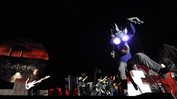 Roger Waters spielt Bassgitarre während einer Aufführung von „The Wall“ mit einer großen Marionette.