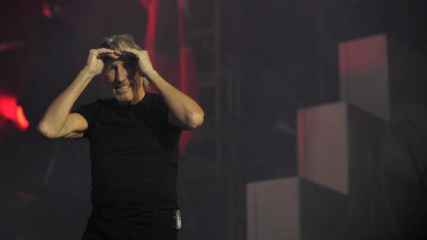 Roger Waters steht auf einer Bühne und formt mit seinen Händen eine Art Visier.