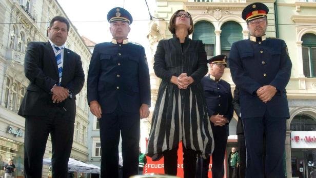 Eine Gruppe von Personen, darunter mehrere in Polizeiuniformen, steht auf einer Bühne.