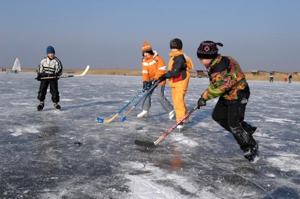 Eine Gruppe Kinder spielt Eishockey auf einem zugefrorenen See.