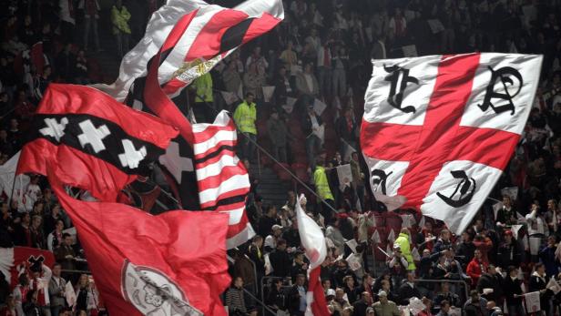 Eine Menschenmenge schwenkt Fahnen mit den Farben und Wappen von Ajax Amsterdam.