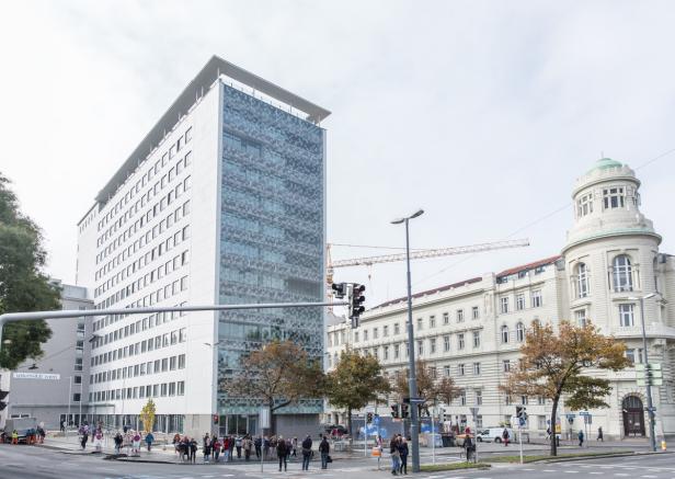 Ein Blick auf die Universität Wien mit Passanten auf dem Gehweg.