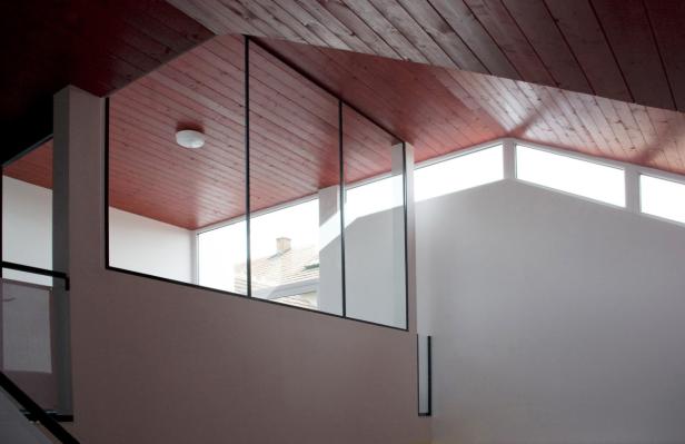 Innenansicht eines Hauses mit Holzdecke und großen Fenstern.