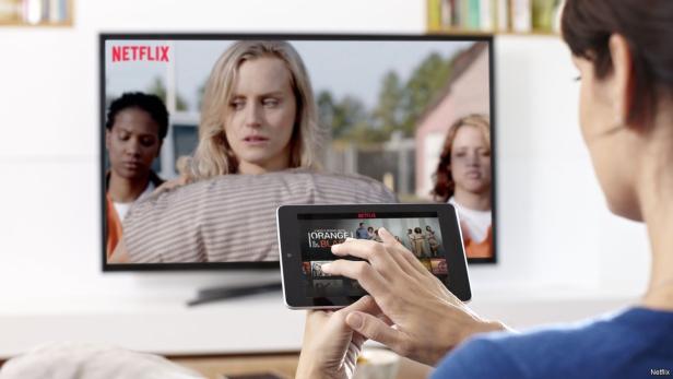 Eine Person schaut „Orange Is the New Black“ auf Netflix, sowohl auf einem Tablet als auch auf einem Fernseher.