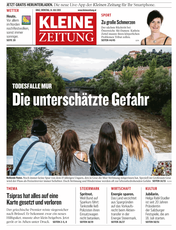 Vier Personen stehen an der Mur und blicken auf das Wasser.