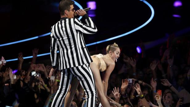Miley Cyrus und Robin Thicke treten gemeinsam auf einer Bühne vor einem Publikum auf.