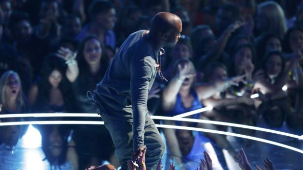 Kanye West steht vor einer jubelnden Menschenmenge.