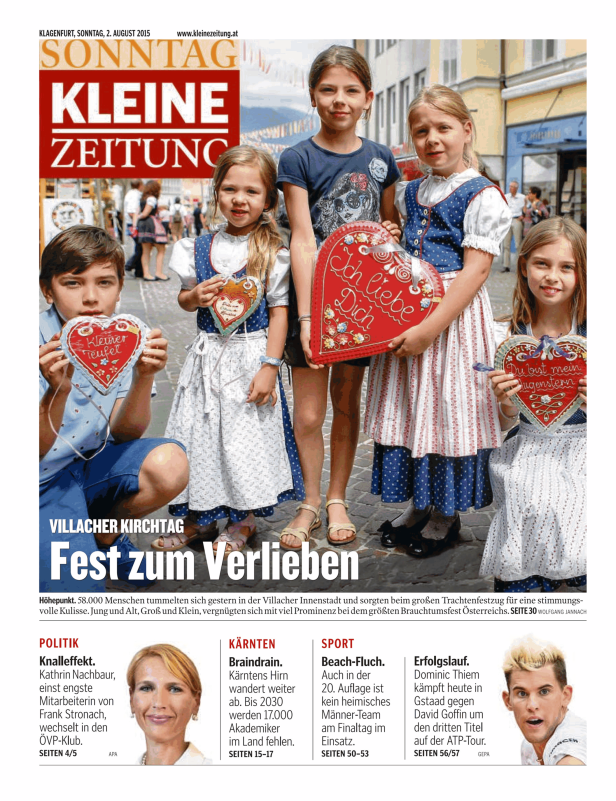 Kinder in Tracht präsentieren Lebkuchenherzen auf dem Villacher Kirchtag.