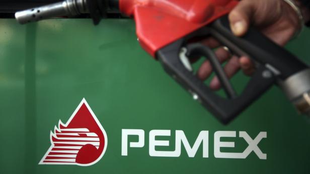 Eine Hand hält eine Zapfpistole vor dem PEMEX-Logo.
