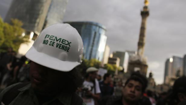 Ein Bauarbeiter trägt einen Helm mit der Aufschrift „PEMEX NO SE VENDE“ vor dem Hintergrund von Mexiko-Stadt.
