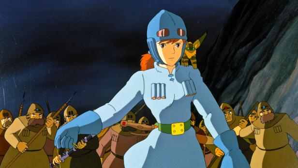 Nausicaä, eine Anime-Heldin in blauer Rüstung, steht vor einer Gruppe bewaffneter Krieger.