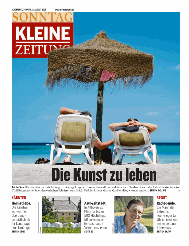 Zwei Personen entspannen unter einem Strohschirm am Strand.
