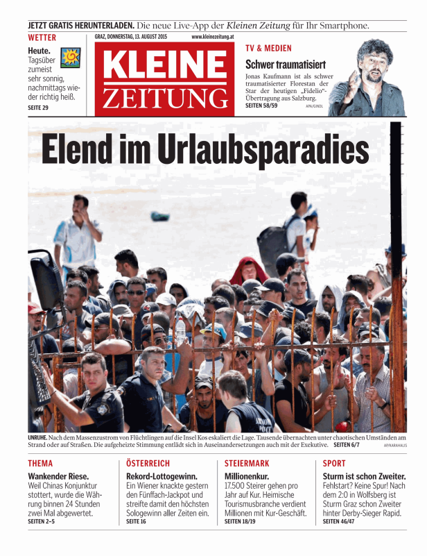 Flüchtlinge und Polizisten stehen hinter einem Zaun auf der Insel Kos.