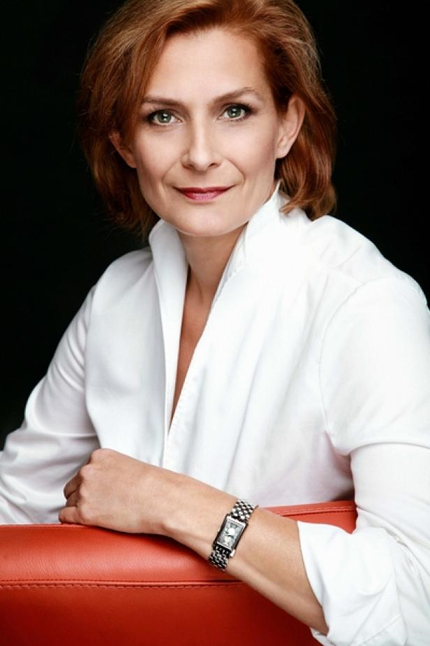 Eine Frau mit roten Haaren und weißem Hemd trägt eine silberne Uhr.