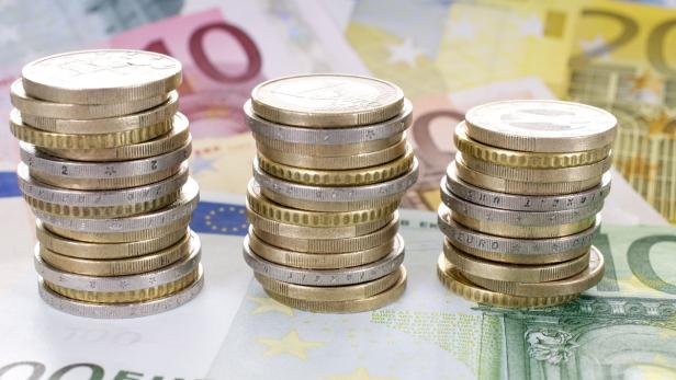 Drei Stapel von Euro-Münzen stehen auf Euro-Banknoten.