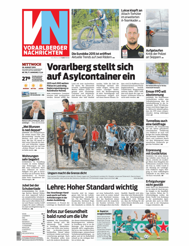 Eine Gruppe von Flüchtlingen, darunter Kinder, an einem Grenzzaun mit Stacheldraht.