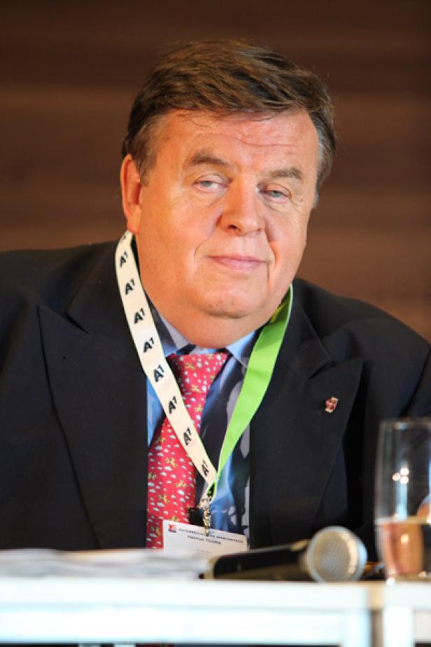 Ein Mann mit Anzug und Krawatte sitzt an einem Tisch.
