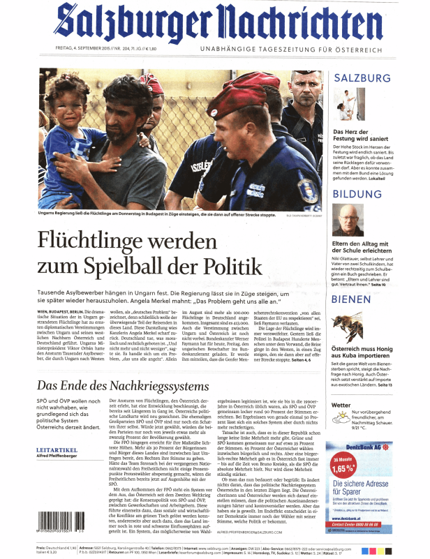 Ein Mann trägt ein weinendes Kind vor einem Zaun, im Hintergrund Polizisten.