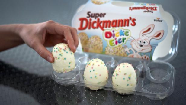 Eine Hand nimmt ein „Super Dickmann's Dicke Eier“-Osterei aus der Verpackung.