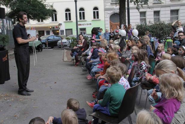 Ein Zauberer tritt vor einer Gruppe von Kindern im Freien auf.