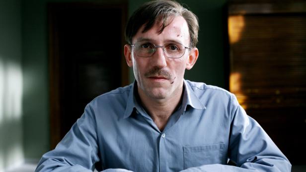 Ein Mann mit Brille und blutigen Kratzern im Gesicht blickt in die Kamera.