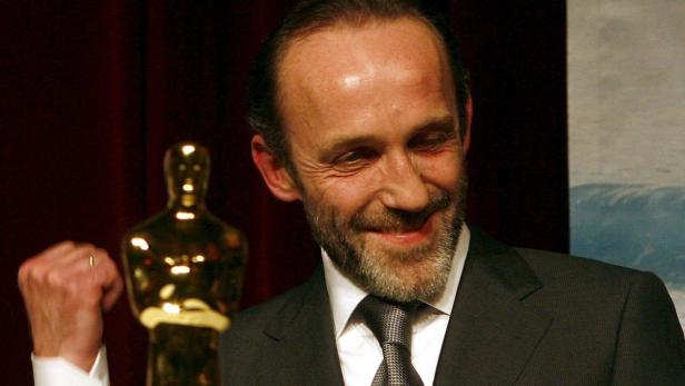 Peter Sarsgaard lächelt neben einer Oscar-Statuette.