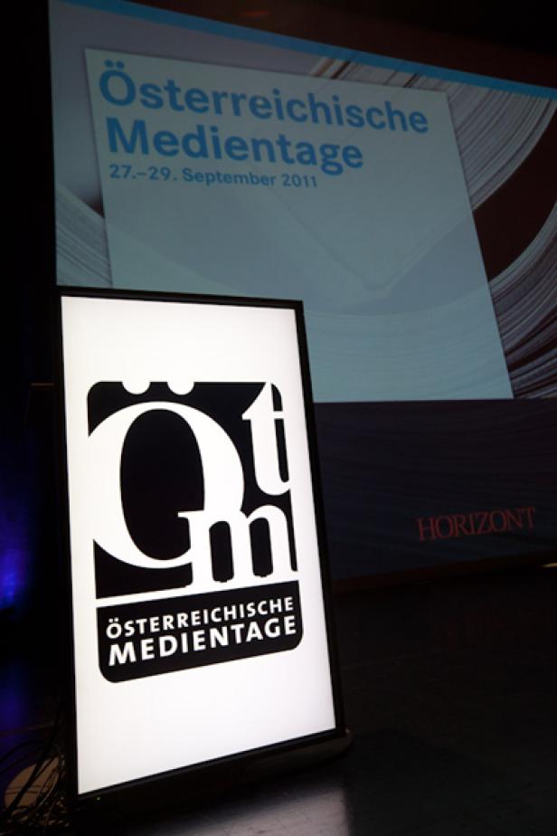 Ein Schild mit dem Logo der Österreichischen Medientage vor einem Bildschirm.