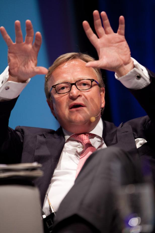 Ein Mann mit Brille gestikuliert während einer Präsentation.