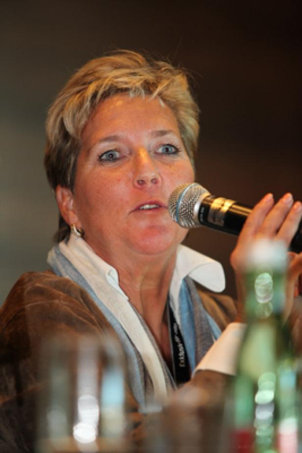 Eine Frau spricht in ein Mikrofon bei einer Konferenz.