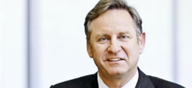 Ein Mann in einem dunklen Anzug lächelt in die Kamera.