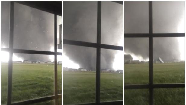 Ein Tornado nähert sich einer Wohngegend, gesehen durch ein Fenster.