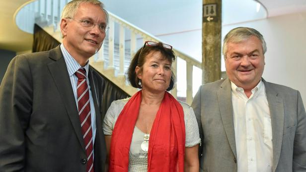 Drei Personen posieren für ein Foto in einem Gebäude.