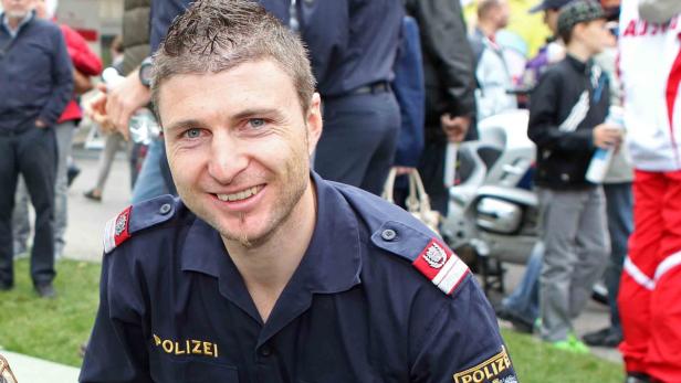 Ein lächelnder Polizist in Uniform, möglicherweise bei einer Veranstaltung.