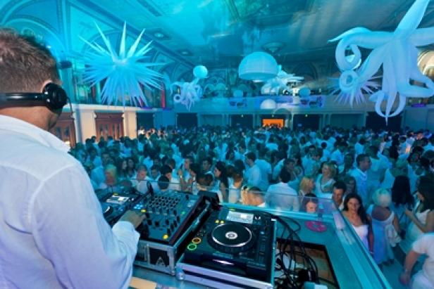 Ein DJ legt bei einer Party auf, bei der alle weiß gekleidet sind.