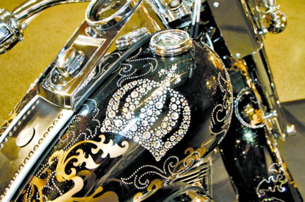 Detailansicht eines Motorrads mit aufwendiger Verzierung aus Strasssteinen und goldenen Ornamenten.