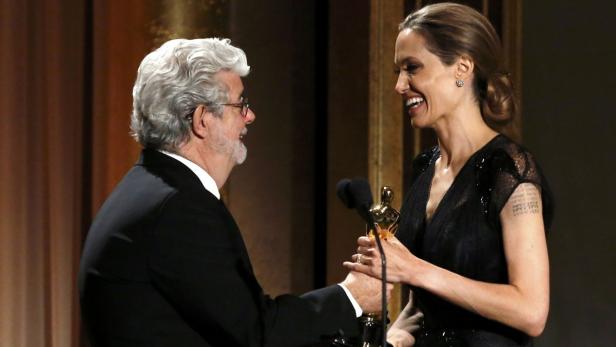 Angelina Jolie und George Lucas halten eine Oscar-Statuette in den Händen.