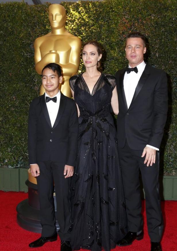 Angelina Jolie, Brad Pitt und ihr Sohn posieren vor einer Oscar-Statue.