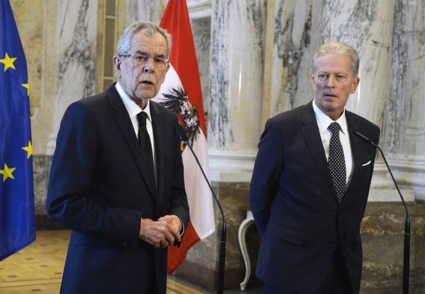 Bundespräsident Alexander Van der Bellen mit einem weiteren Mann vor Flaggen der EU und Österreichs.