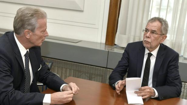 Bundespräsident Alexander Van der Bellen im Gespräch mit einem Mann am Tisch.