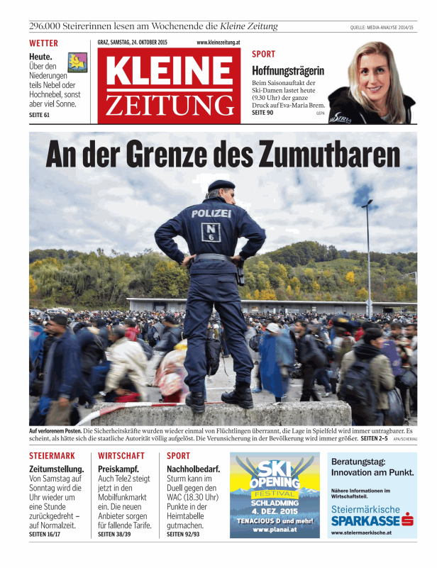 Ein Polizist steht vor einer Menschenmenge, möglicherweise an einer Grenze.