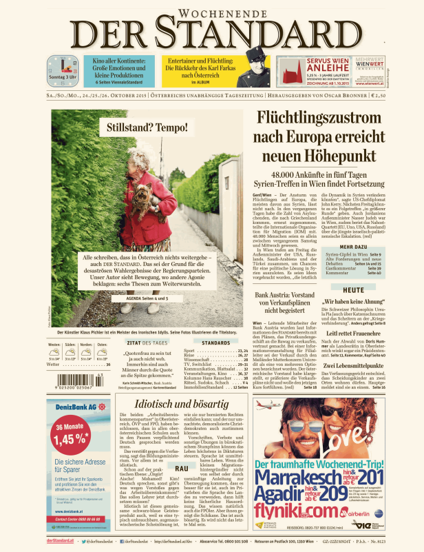 Eine ältere Frau mit einem kleinen Hund auf dem Arm steht hinter einer Hecke.