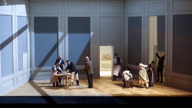 Auf einer Theaterbühne bereiten sich Schauspieler in einem eleganten Raum vor.