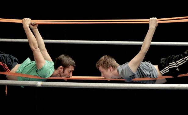 Zwei Männer trainieren mit Gummibändern und Metallstangen.