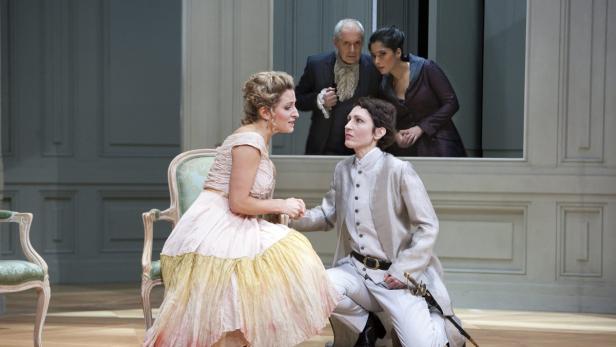 Szene aus einem Theaterstück mit zwei Frauen im Vordergrund und zwei Personen im Hintergrund.