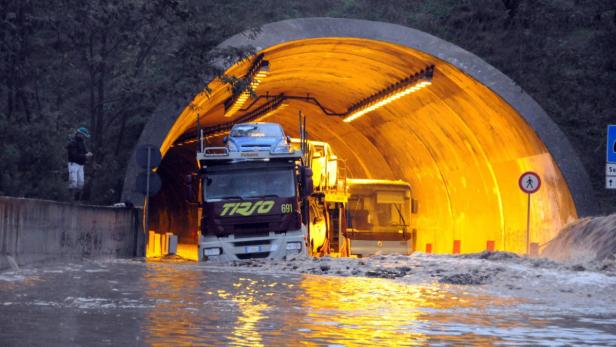 Ein Autotransporter und ein Bus stehen im überfluteten Eingang eines Tunnels.